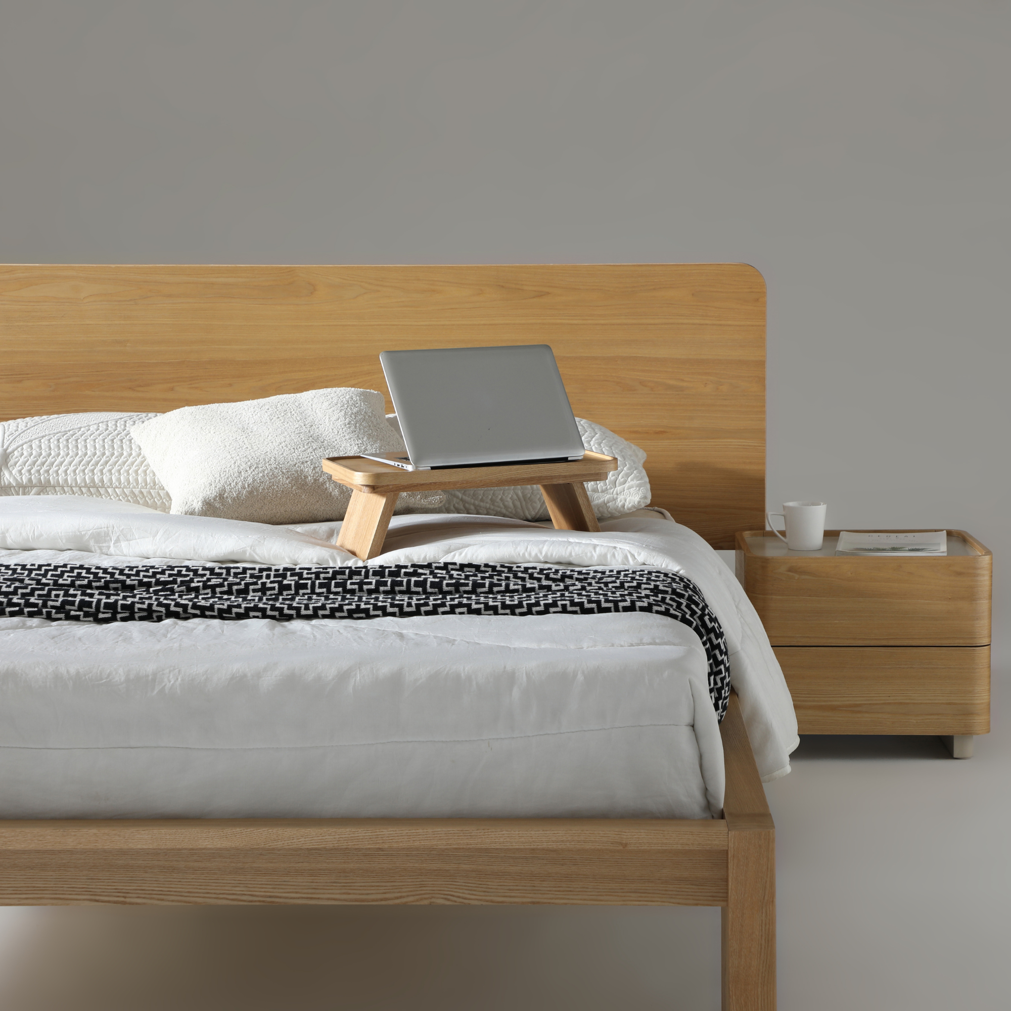 Xara natural ash queen size bed with a laptop table, cozy bedding, and modern nightstand.