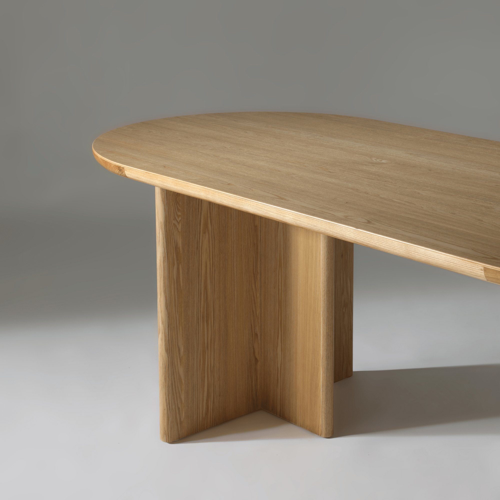 Close-up view of the Kiama 2m Dining Table in natural ash, showcasing its elegant curved edges and sturdy wooden base.