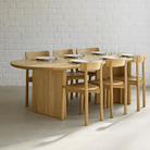 Kiama 2m Natural Ash Dining Table with elegant curved edges and wooden chairs, set for a stylish dining experience.