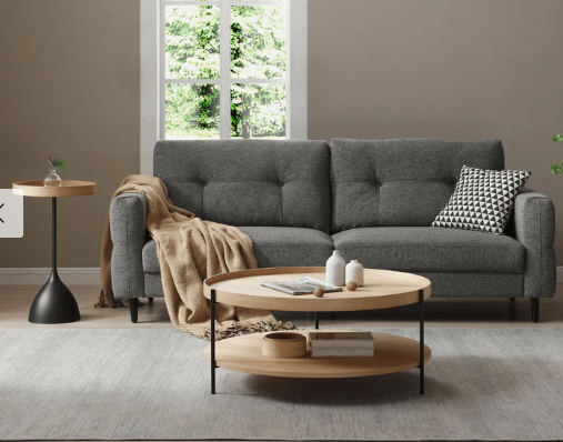 Modern coastal coffee table, 90 cm round in ash with black steel legs and low storage shelf, styled in bright beachy living room.