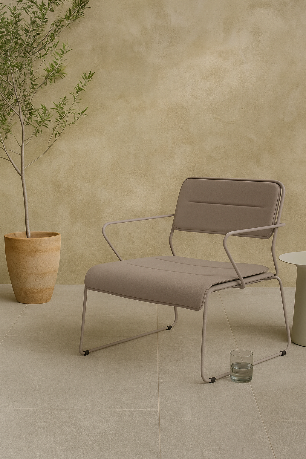 Parco Outdoor Armchair in sand color, featuring plush cushions, set against a minimalist backdrop with potted plant.