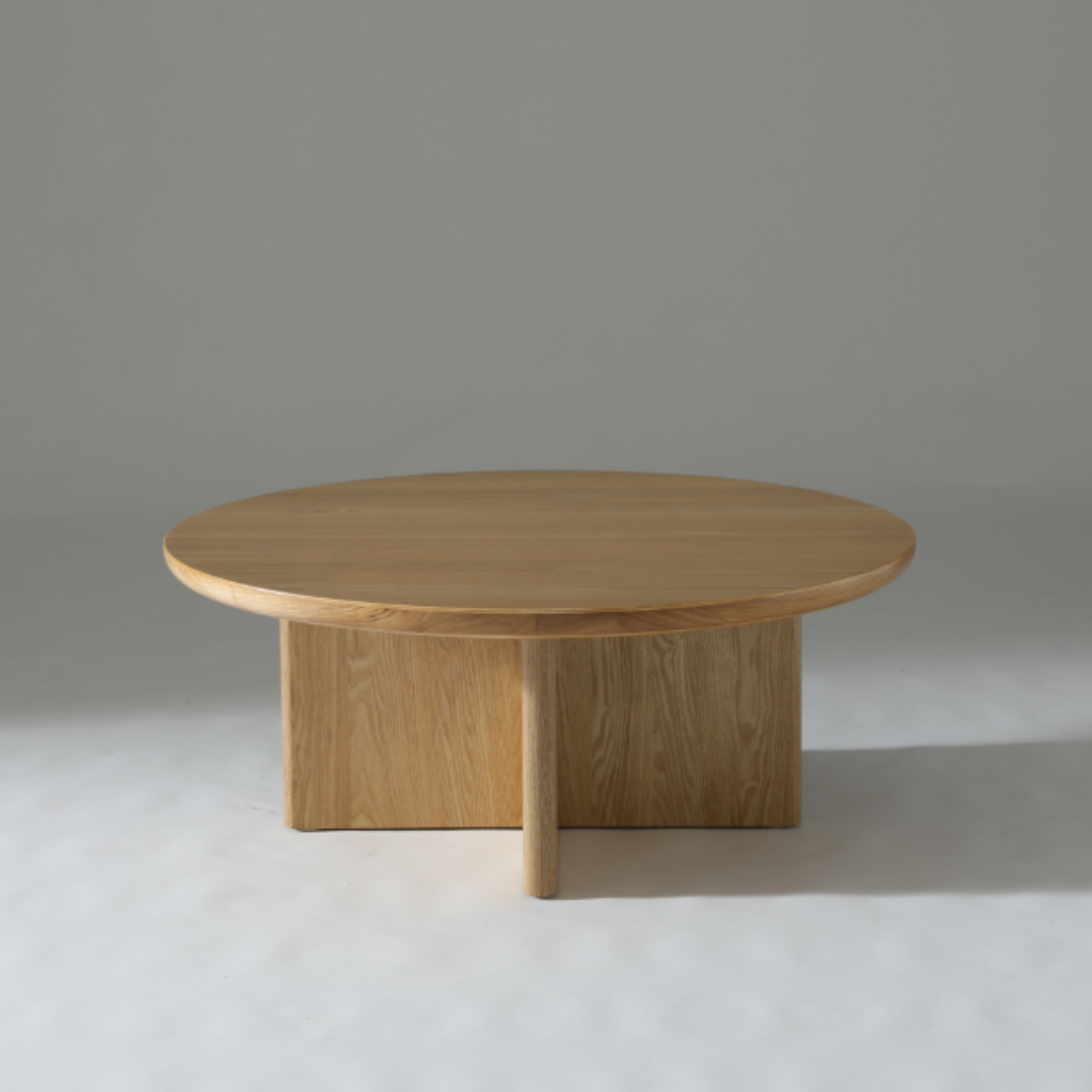 Natural Ash round coffee table featuring a smooth veneer finish and contemporary silhouette.

