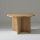 Natural Ash round dining table with subtle wood grain and light, modern coastal style.