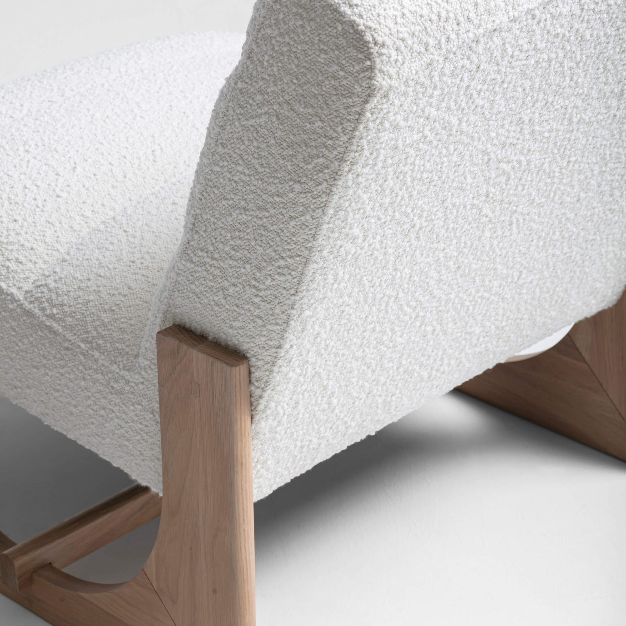Plush boucle lounge chair with oak timber detailing and minimalist modern design.