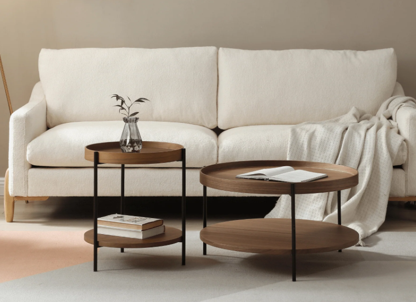 Modern walnut side table, 40 cm round with storage shelf and black steel legs, styled beside a linen sofa with books and ceramic vase.